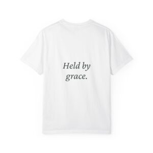 Back view of a white T-shirt showing the text 'Held by grace.' in dark cursive across the back.