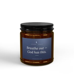 Close-up of a brown glass bottle with a dark blue label that reads 'Breathe out – God has this' and a black cap.