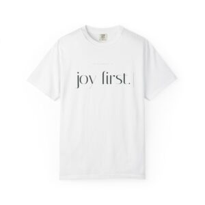 White T-shirt with the words 'joy first' printed in large, stylish black letters across the chest, tag visible at the neckline.