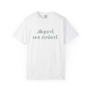 White T-shirt laid flat with black typographic slogan: 'aligned, not rushed.' on the front.