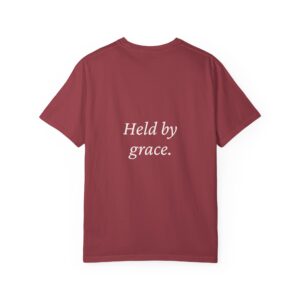 Back view of a maroon t-shirt with white cursive text that reads 'Held by grace'.